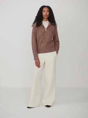 A person wearing a VARLEY - SHERIDA HALF-ZIP KNIT SWEATER IN GINGERBREAD FLECK, a brown speckled boucle yarn sweater with a collared half-zip neckline.