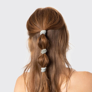 A KITSCH set of 20 eco-friendly nylon elastics in muted green, made from recycled materials. These essential hair ties come packaged under the "KITSCH" brand, displayed on hanging packaging with brand and product details.