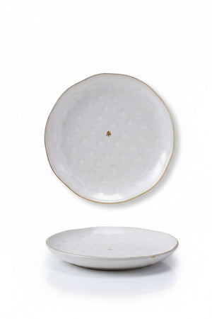 A DEBOSSED PLATE WITH GOLD ELECTROPLATING and matching mug with a reactive glaze and debossed gold Christmas tree patterns, containing macarons and marshmallows next to a printed holiday program.