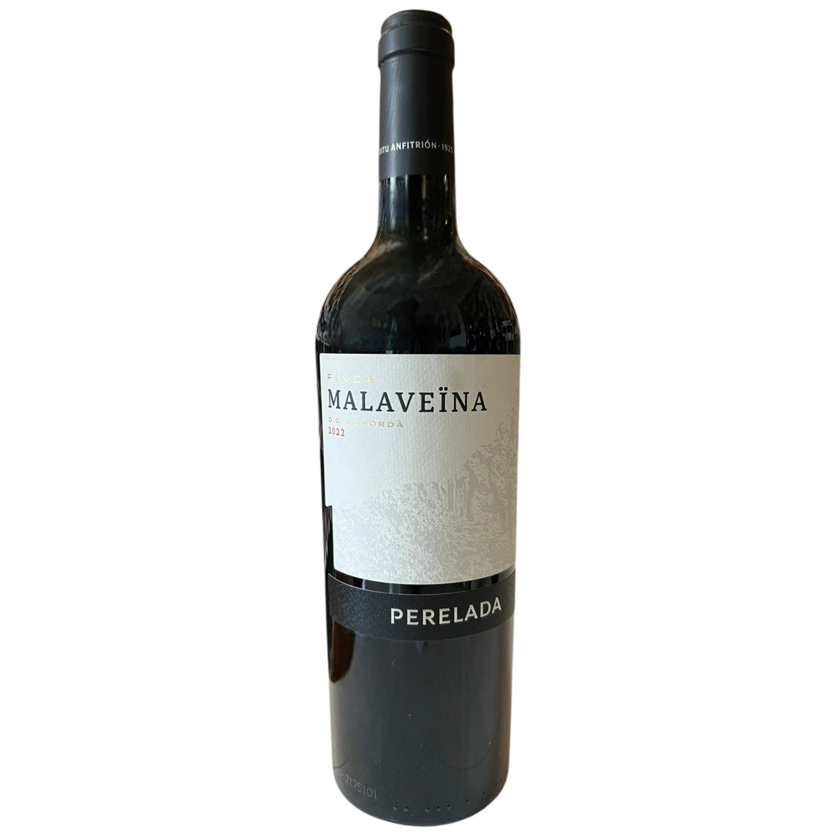 A PERELADA 'FINCA MALAVEÏNA' MERLOT BLEND 2019 wine bottle from Empordà, Spain, features a black label with silver text and a horse-drawn carriage logo. The black cap elegantly displays "Malaveïna" in silver lettering. Enjoy its smooth tannins. Brand: WINE: JOHNSON BROS./MUTUAL/EPIPHANY.