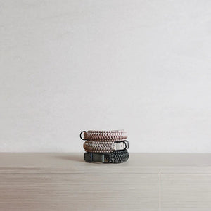 Two LAMBWOLF COLLECTIVE NEW JUPITER Dog Collars in small, one in beige and one in gray, are stacked on a light wooden surface against a plain, light-colored wall. Designed by LAMBWOLF COLLECTIVE, each collar combines cushioned comfort with sturdy durability, making them perfect for everyday wear.