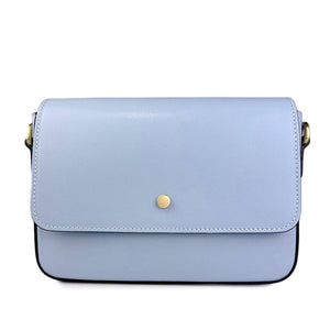 The RIGID LEATHER HANDBAG by MIRAMI FIRENZE is a cream-colored leather handbag with a minimalist design. It features a flap closure with a single metallic button in the center, black edging, brass hardware on the strap attachments, and an adjustable shoulder strap for versatility. Crafted from real leather, it also includes internal pockets for organization.