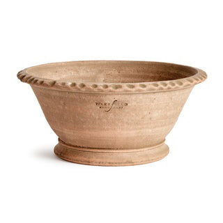 The NAPA HOME AND GARDEN - WAKEFIELD ALVENA FORCING POT holds tall white orchids with green leaves and buds. The beige handmade terracotta pot is shown on a white background with the caption &quot;WITH DROP-IN K112W&quot; below.