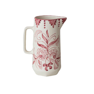 The HAND-PAINTED STONEWARE PITCHER WITH BOTANICAL DESIGN by CREATIVE COOP features a white ceramic finish, handle, and pink floral and swirl patterns with decorative dots, capturing charming cottagecore style on a plain background.