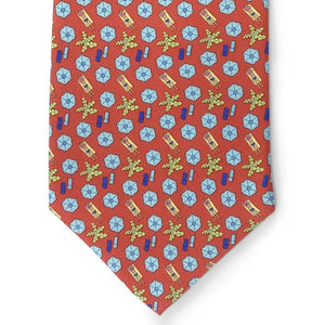 A rolled-up red necktie featuring a repeating pattern of pink beach umbrellas, yellow-green palm trees, and blue beach towels, the Peter-Blair Sunscreen Silk Tie by Bird Dog Bay is handmade in New York and finished with the signature Peter-Blair woven label.