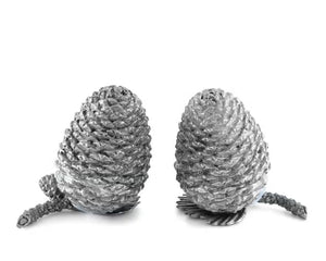 Two detailed silver pine cones stand upright on a white background, resembling the VAGABOND HOUSE - PEWTER PINE CONESALT AND PEPPER SET by VAGABOND HOUSE, with small pine needle segments visible at their bases.