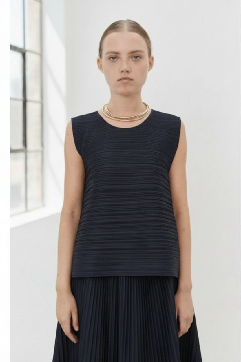 Close-up of MEIMEIJ Plisse Sleeveless Top's dark textured fabric displays a finely woven pattern. The consistent monochrome color and texture, with subtle weave variations, reflect minimalist elegance.