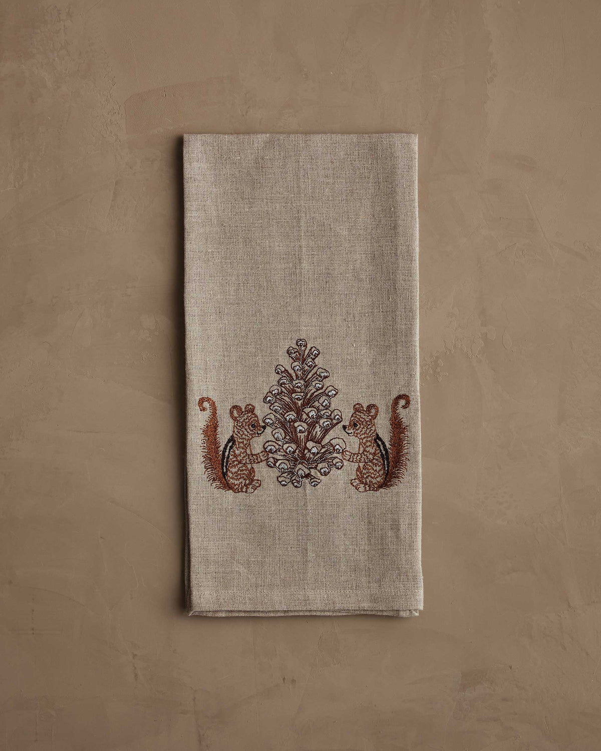 CHIPMUNKS WITH PINECONE LINEN TEA TOWEL by CORAL & TUSK featuring embroidered chipmunks holding a large, stitched pinecone.