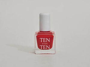 A glass bottle of TENOVERTEN - NAIL POLISH from the brand TEN OVER TEN, featuring a white cap and a dusty pink nail color. The front label displays "TEN OVER TEN" in white uppercase letters. This vegan, eight-free formula ensures both beauty and peace of mind. The background is plain and light-colored.