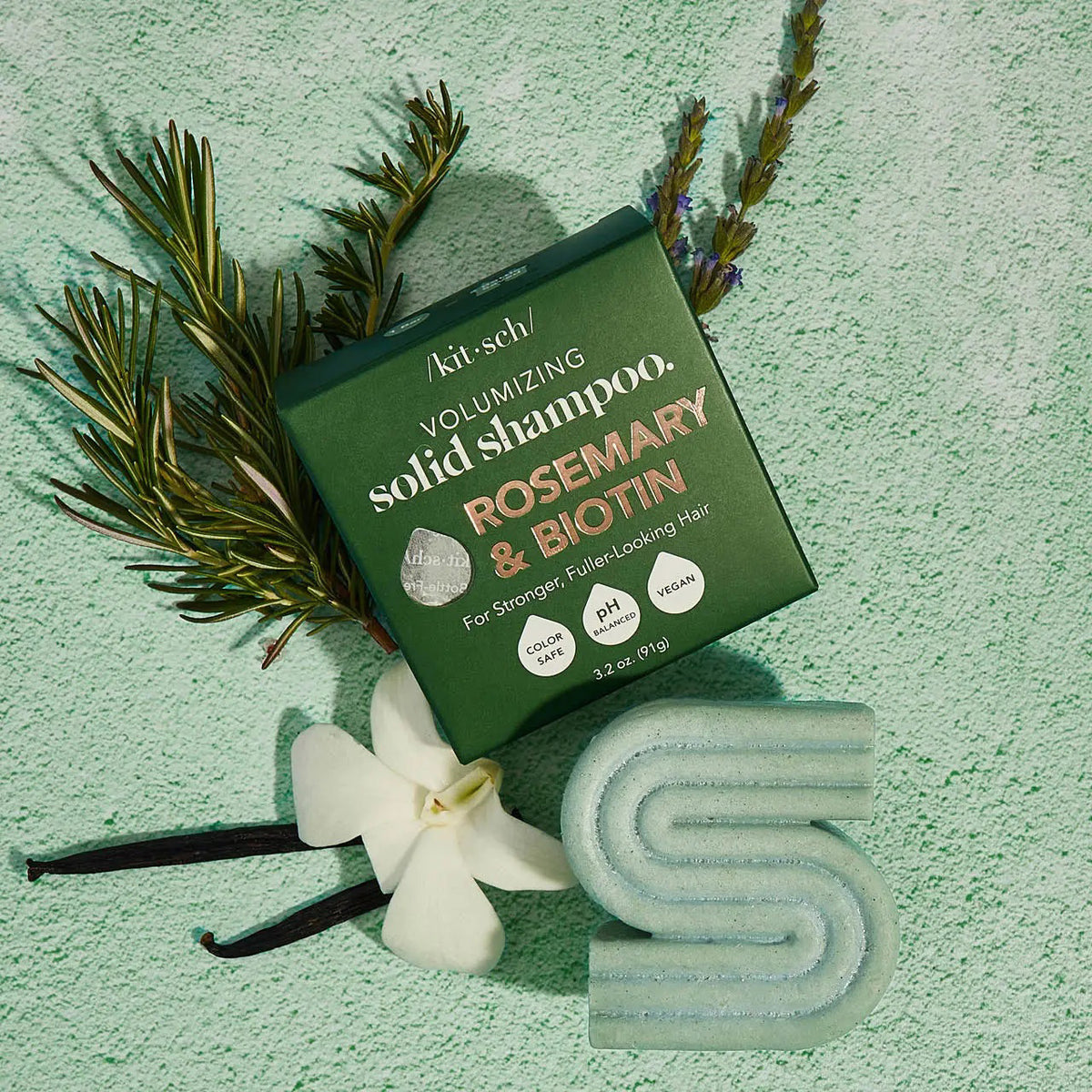 A green KITSCH box labeled “Rosemary and Biotin Volumizing Solid Shampoo Bar” stands behind a matching bar for hair growth; the 3.2 oz (91g) vegan formula is color safe and pH balanced.
