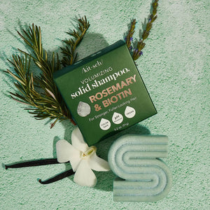 A green KITSCH box labeled “Rosemary and Biotin Volumizing Solid Shampoo Bar” stands behind a matching bar for hair growth; the 3.2 oz (91g) vegan formula is color safe and pH balanced.