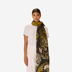The INOUI EDITIONS - PAPILLONS SCARF IN KHAKI by INOUI is a rectangular linen scarf hand-printed with yellow, white, green, and black butterflies on a dark green background—perfect for elevating your khaki scarf collection.