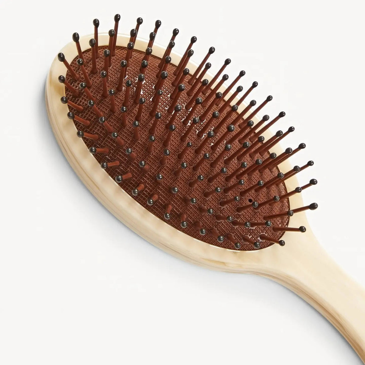 The MACHETE Everyday Detangling Hair Brush in Alabaster features an ivory marbled Italian acetate design, oval head, and curved handle with concealed bristles, shown from above on a plain white background.