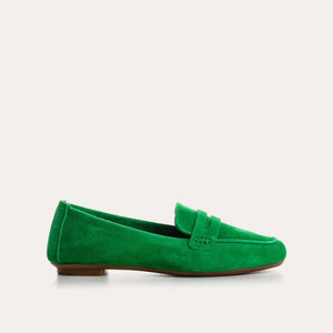 A person stands on a light floor wearing blue jeans and REQINS - HEMA SUEDE LOAFER IN GAZON GREEN by REQINS, featuring a leather insole.