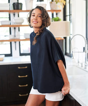 The FRANK & EILEEN Audrey Funnel Neck Capelet in British Royal Navy is a simple, loose-fitting dark navy blue t-shirt. Made from 100% cotton fleece, it features a high neckline and short sleeves with a boxy, relaxed silhouette against a white background.