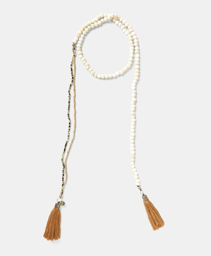 The MOMONI - NOEL NECKLACE by MOMONI features colorful round glass beads and two brown cotton tassels at each end, shown against a white background.