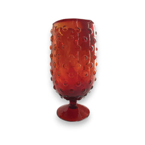 The CREATIVE COOP RED HOBNAIL DRINKING GLASS features a raised dot pattern and short stem, shown against a white background.