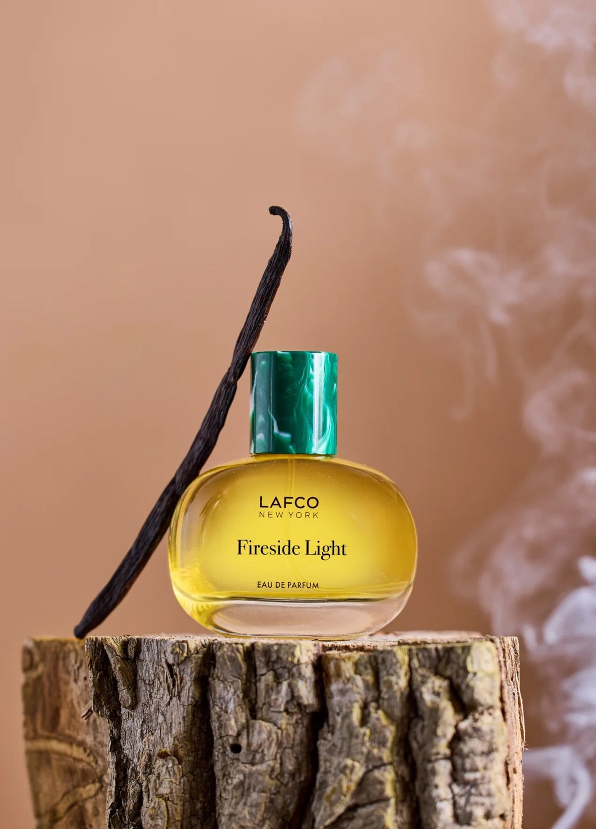 A round glass bottle of LAFCO Fine Fragrance, Fireside Light 50ml, a vegan perfume with a long-lasting scent, contains yellow liquid and is topped with a marbled green cap, displayed against a plain white background.