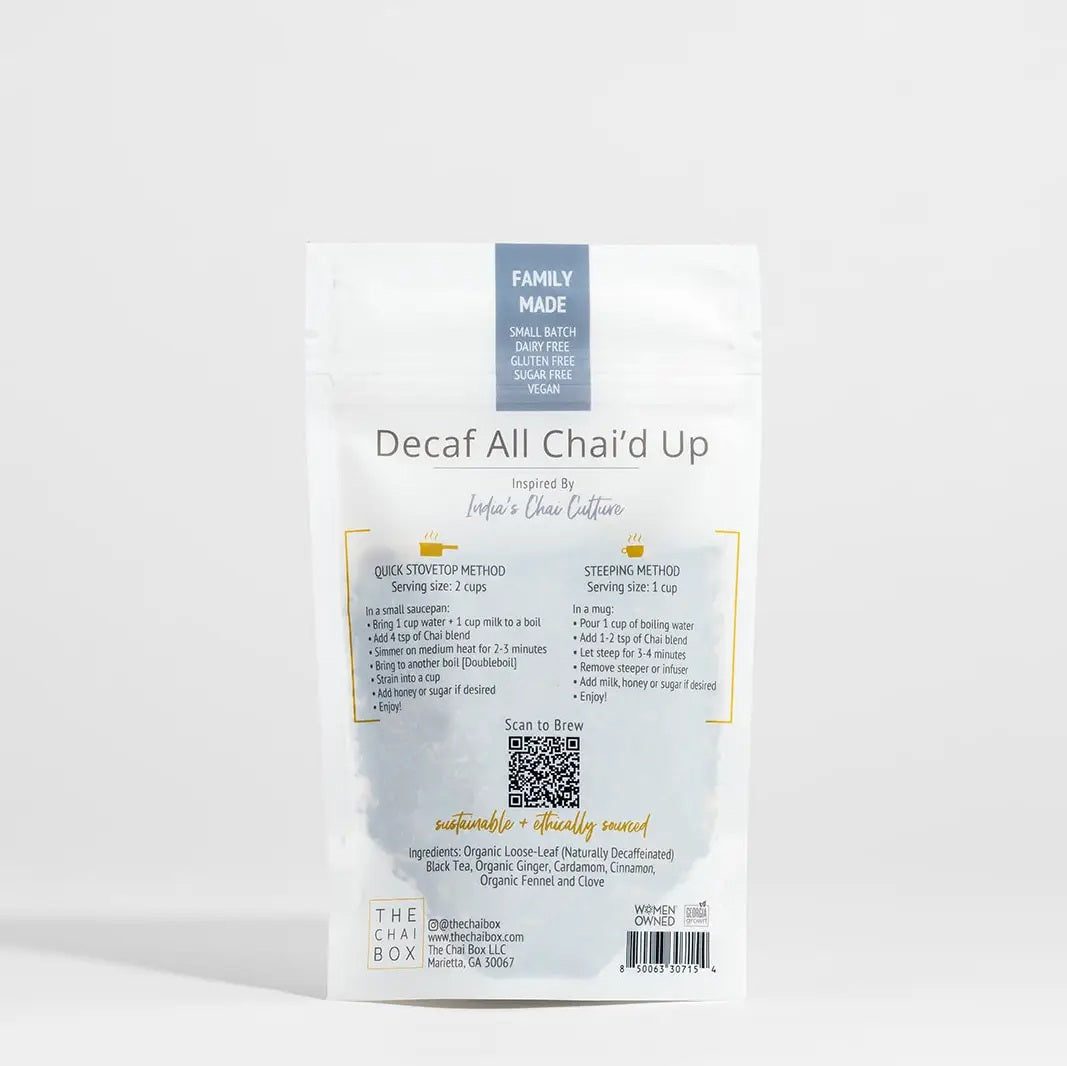 A white pouch labeled “THE CHAI BOX - DECAF ALL CHAI’D UP” from THE CHAI BOX contains an organic spiced tea blend crafted with naturally decaffeinated black tea. The package indicates it yields 20-25 cups and is hand blended on the Atlantic Coast.