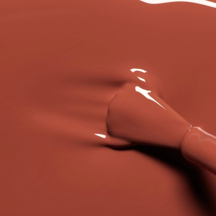 A chart displaying twelve lipstick shades—each swatched alongside its name and color description—features a range of reds and oranges, from coral and cherry to terracotta, pomegranate, and deep berry tones. These hues are designed to perfectly complement your favorite vegan nail polish or pair flawlessly with MANUCURIST - GREEN™ NAIL POLISH IN BRICK by MANUCURIST INC for a coordinated, striking look.