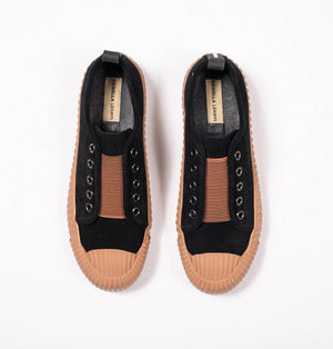 Introducing the DANIELLA LEHAVI - OSAKA SNEAKER by DANIELLA LEHAVI: Black sneakers featuring brown rubber soles and decorative brown straps across the top. They highlight a contemporary design with circular metal eyelets on the sides and are presented on a white platform against a simple, light-colored background.