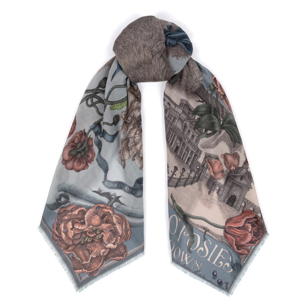 A person wearing a light-colored dress drapes the SABINA SAVAGE - RING A RING O' ROSES cashmere scarf in Glacier/Ballet over their shoulders, featuring intricate floral designs reminiscent of English garden flowers. The muted hues contrast beautifully against its soft blue-gray background.