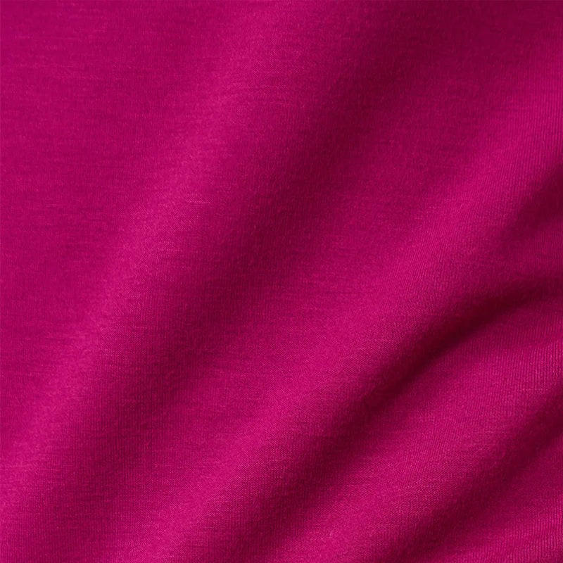 A woman seen from behind wearing the fuchsia SOFTIES - DREAMTECH COWL NECK WITH PLEATED PANT set featuring a long-sleeved cowl neck top and matching pleated pants.