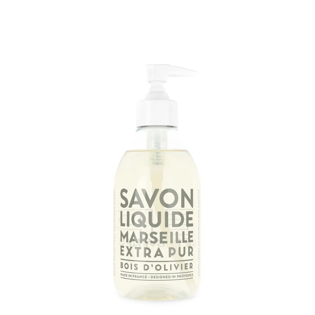 A clear pump bottle of COMPAGNIE DE PROVENCE Liquid Marseille Soap Olive Wood 10oz by CIE LUXE BRANDS, with a light-colored soap and a white pump dispenser. White label text reads &quot;Savon Liquide Marseille Extra Pur Bois d’Olivier.