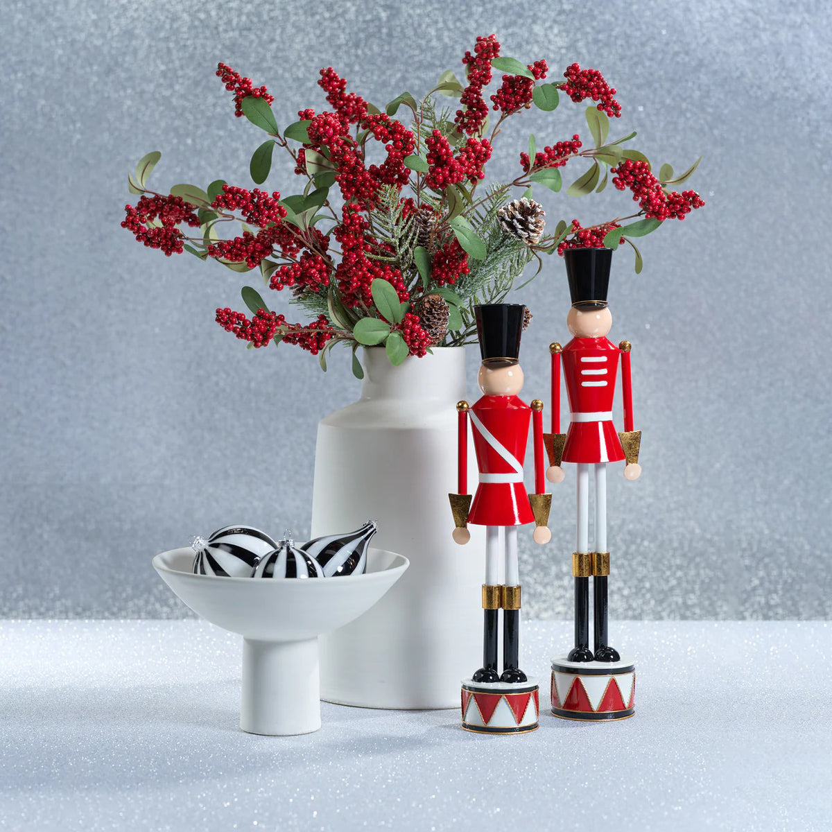 The ZODAX ALLOY FESTIVE DECORATIVE SOLDIER - SHORT features a red uniform with white stripes, black hat and boots, and stands on a round base with a red and white drum pattern; measures 4.5 x 17.75 inches for a striking display.