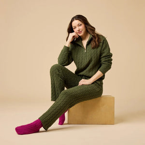 A woman wearing a marshmallow-soft, cream-colored SOFTIES - CABLE KNIT MARSHMALLOW ½ ZIP WITH TAPERED PANT SET, featuring a half-zip pullover and matching pants with a drawstring waist.