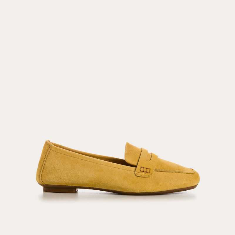 The REQINS - HEMA Suede Loafer in Ochre, expertly crafted by REQINS, features a low heel and a decorative front strap, shown against a plain light background.