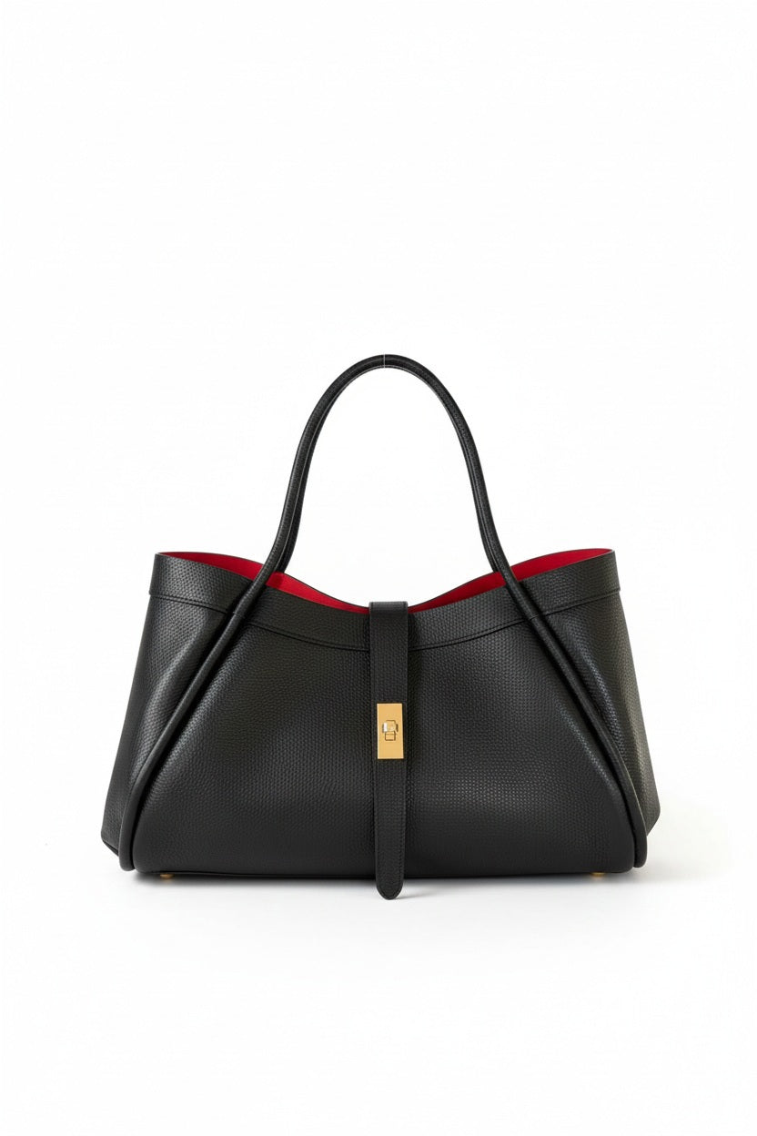 THE PORTICO LEATHER HANDBAG IN BLACK is a structured Italian luxury bag in black leather with a central clasp and contrasting red interior.