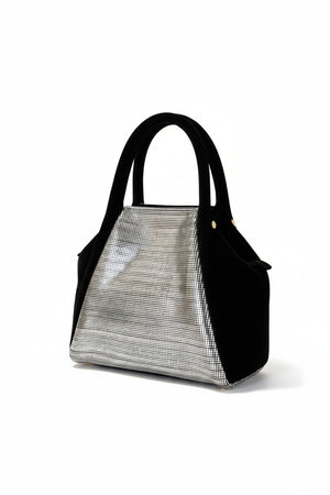 The OLIVEVE Mini Taya Top Handle, crafted from Italian leather in black, boasts a sleek modern design with a metallic front panel reflecting distorted images. This elegant handbag features two handles and stands out against its plain white backdrop.