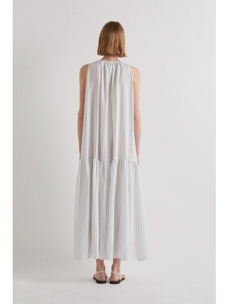 A person stands against a plain white background, wearing the MEIMEIJ Sleeveless Maxi Dress with Stripes, an ankle-length summer piece styled with flat sandals and a statement necklace for an effortlessly chic look.