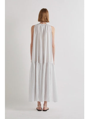 A person stands against a plain white background, wearing the MEIMEIJ Sleeveless Maxi Dress with Stripes, an ankle-length summer piece styled with flat sandals and a statement necklace for an effortlessly chic look.