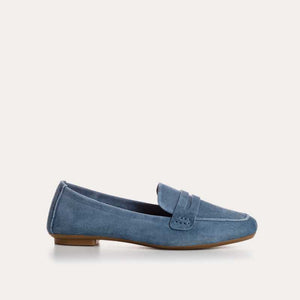 The REQINS - HEMA suede loafer in Blue Jean features a classic silhouette, minimalist design, penny strap, and brown soles, shown against a plain white background.