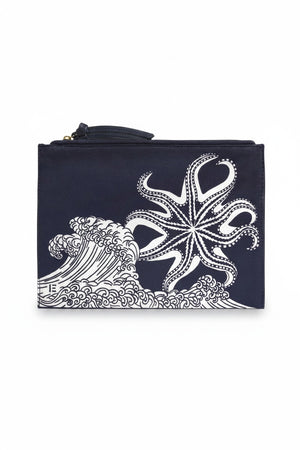 INOUI EDITIONS - POSEIDON POUCH IN NAVY by INOUI features vertical navy and white stripes, a navy zipper, and a small square patch on the front. Inspired by traditional weaving for timeless style, shown against a plain white background.