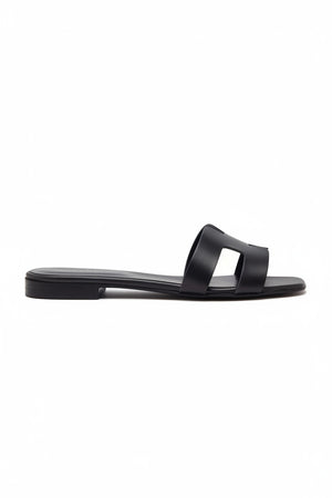 The MICHELE LOPRIORE - H SLIDE is a brown leather sandal with two wide straps, including one with a rectangular cutout, featuring a flat wooden sole. Made in Italy by MICHELE LOPRIORE, it's shown on a white background.