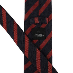 A close-up of the AMANDA CHRISTENSEN - STRIPED JACQUARD WOVEN SILK TIE IN RUST reveals its elegant red diagonal stripes on luxurious Italian silk, with a label bearing the AMANDA CHRISTENSEN name against a white background—an exceptional men’s formal accessory perfect for any refined occasion.