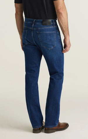 A person is shown from the back wearing a black shirt and the 34 HERITAGE - CASH BOOTCUT JEANS IN DARK BRUSHED VINTAGE by 34 HERITAGE. The vintage denim features back pockets and a black leather patch on the waistband, with the wearer’s arms visible.