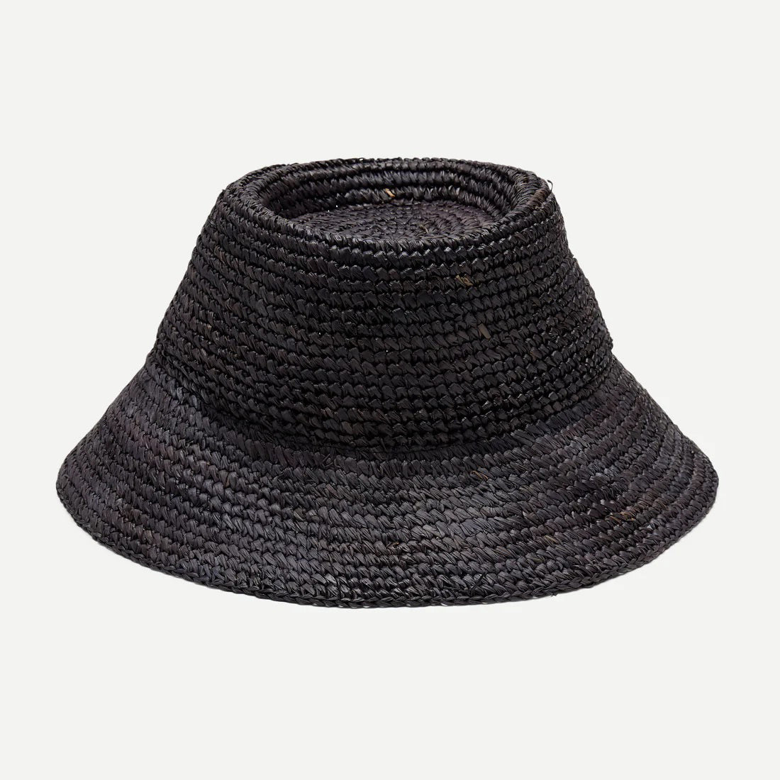 A woman with long, wavy blonde hair wears a sleeveless white top and the WYETH HATS - TALI Raffia Bucket Hat in Midnight by WYETH, featuring an adjustable fit, shown in profile against a plain light background.