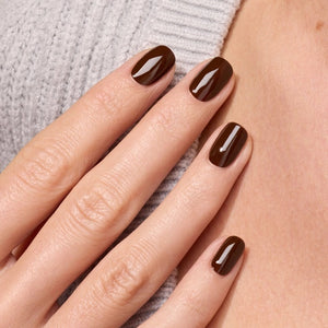 A bottle of MANUCURIST - GREEN™ Nail Polish in Clove by MANUCURIST INC, featuring a rich chocolate brown shade and a black cap. The label reads “green quick dry intense color.”.