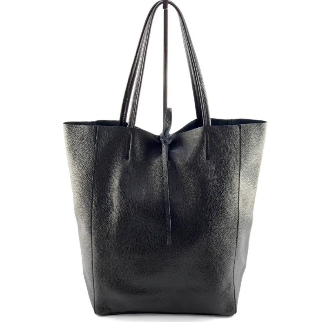 The LEATHER TOTE BAG IN BLACK by JIJOU CAPRI, featuring double handles and a simple tie closure, is crafted from Italian leather and stands upright against a white background—ideal for carrying your daily essentials.