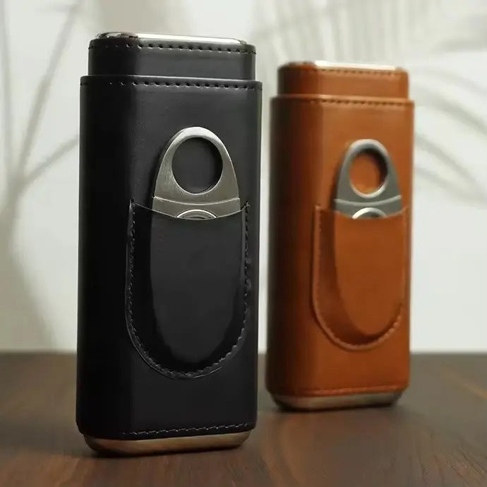 The AMERICAN LEATHER GOODS Leather Cigar Case with Wood-Lined Humidor and Cutter in Black rests on a wooden surface, with another travel humidor case in brown visible in the background.