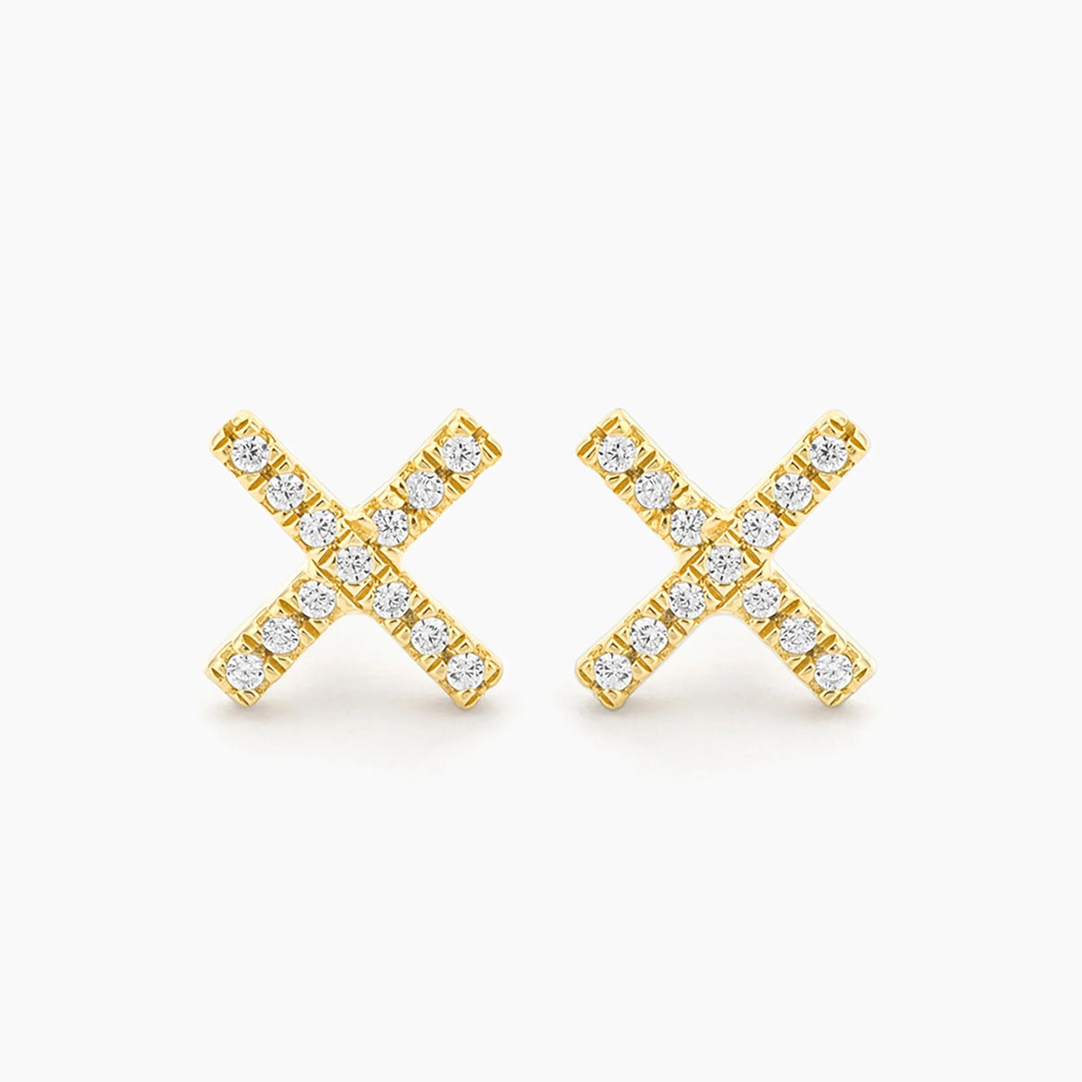 Close-up of a woman’s ear with straight brown hair, wearing the ELLA STEIN - HUG IT OUT STUD EARRINGS, gold plated and “X”-shaped by ELLA STEIN, against a plain light background.