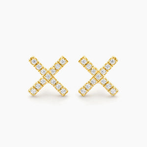 Close-up of a woman’s ear with straight brown hair, wearing the ELLA STEIN - HUG IT OUT STUD EARRINGS, gold plated and “X”-shaped by ELLA STEIN, against a plain light background.