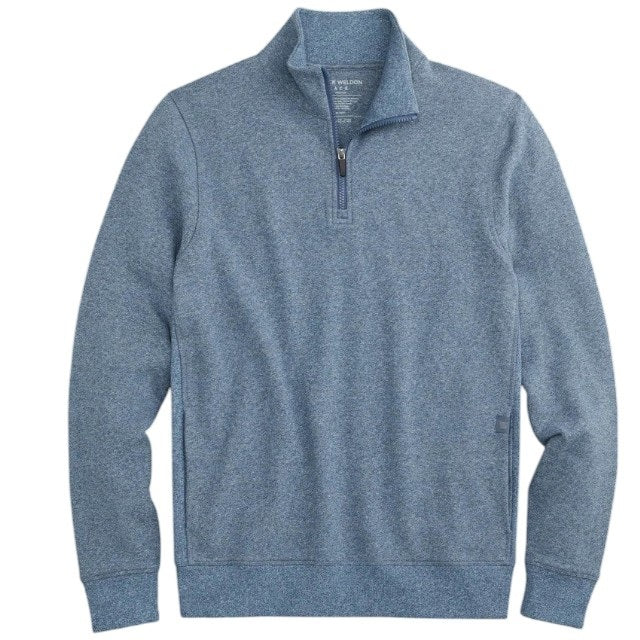 A man with short light brown hair stands in profile, wearing the MACK WELDON Ace 1/2 Zip Sweater in Herringbone and dark pants, one hand in his pocket, against a plain light gray background.