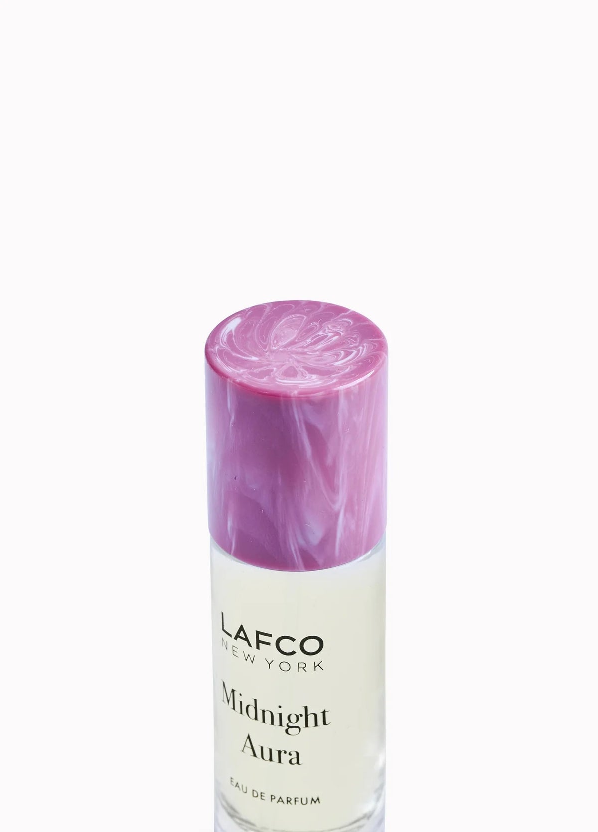 A person holds a 10ml bottle of LAFCO Fine Fragrance, Midnight Aura, on their bare shoulder against a soft purple background.