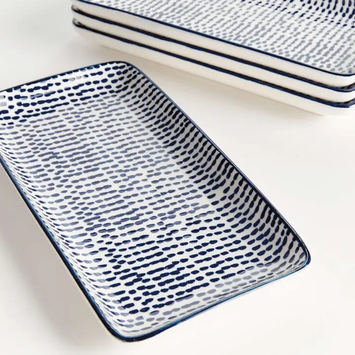 The NAPA HOME AND GARDEN Blue and White Speckled Stria Tray features a rectangular ceramic design with slightly raised edges, ideal for modern dining decor. Shown here set on a light-colored surface.