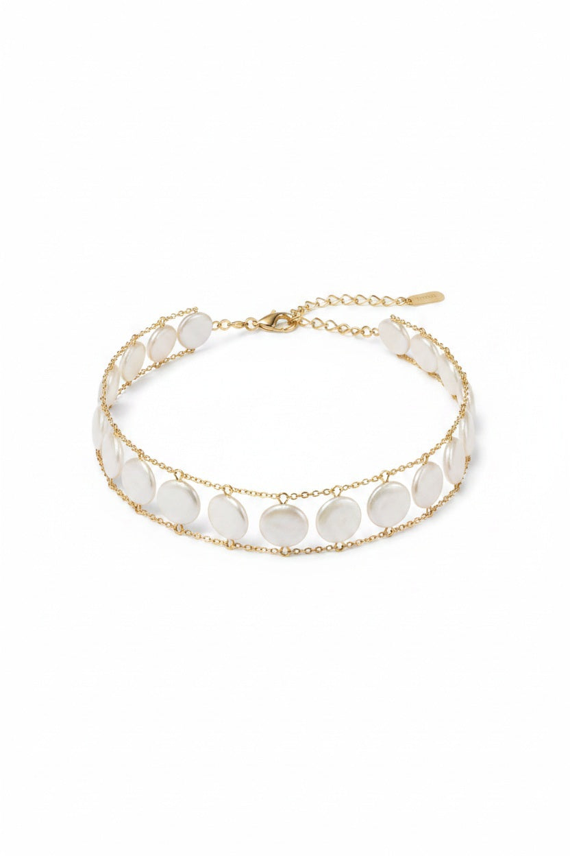 A woman wears the GOLDISH - LADDERS TO BLISS WHITE PEARL CHOKER by GOLDISH, a double-layered lightweight necklace with round white pearls on a gold linked chain, shown against a neutral background.